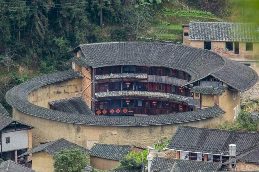 A traditional multi-story building with a curved roof, surrounded by smaller structures and vegetation. 2