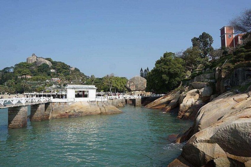A coastal area with a bridge, rocky shoreline, and a hill with a fort. 5