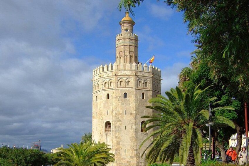 Ein historischer Turm mit einer Uhr, umgeben von Palmen und blauem Himmel. 3