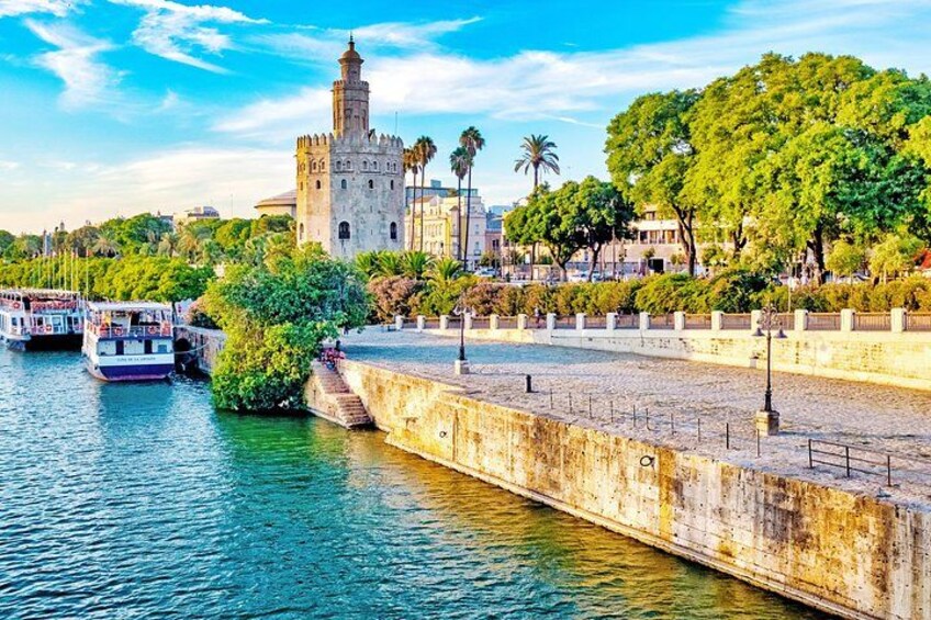 A river with boats, a historic tower, and a park with trees. 4