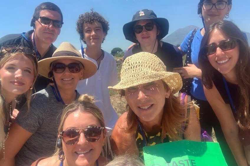 A group of people outdoors, some wearing hats, with a green sign in the foreground. 2