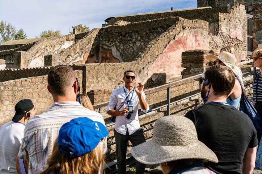 Un sitio histórico con ruinas y un guía acompañando a un grupo de turistas. 2