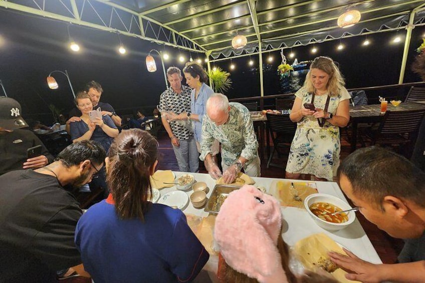 A group of people dining outdoors at night, with string lights overhead. 3