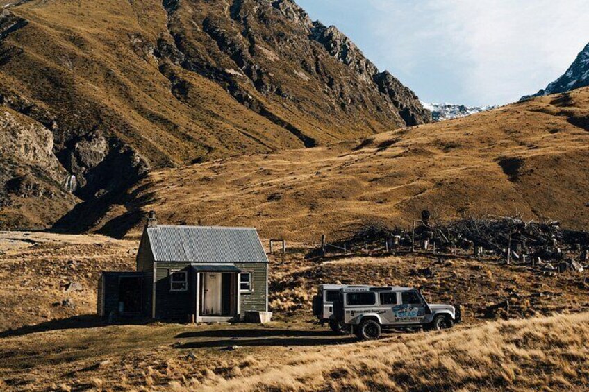 A small house with a truck parked in front, surrounded by a mountainous landscape. 2