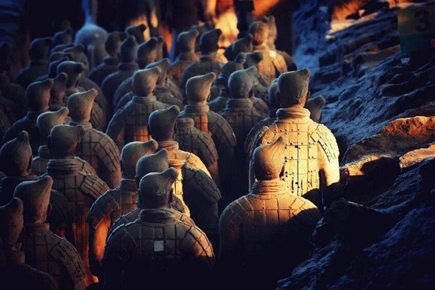 Terracotta soldiers lined up in rows, some with inscriptions, in a historical site. 2