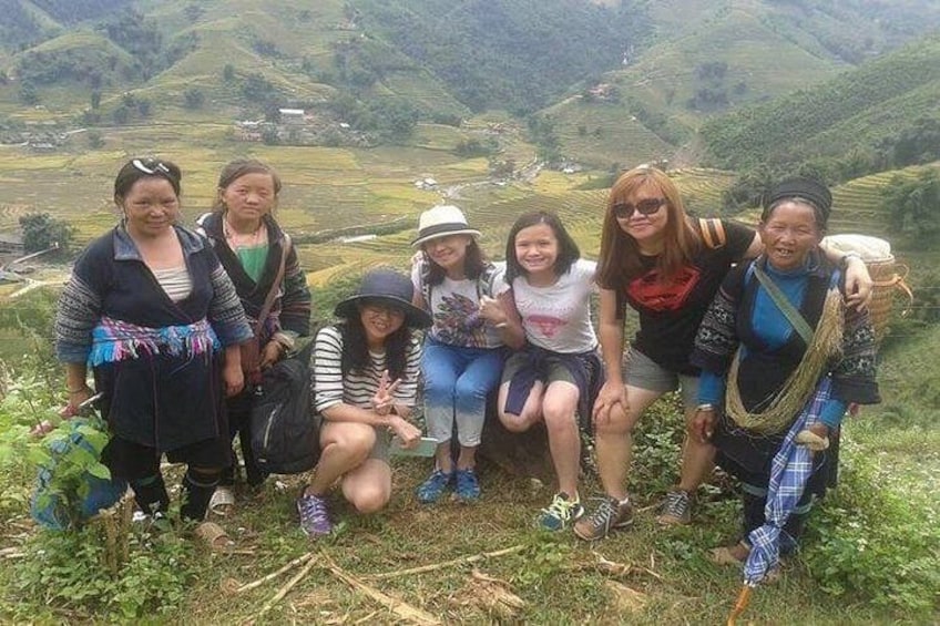 Een groep mensen die poseert op een grasheuvel, met een bergachtig landschap op de achtergrond. 4