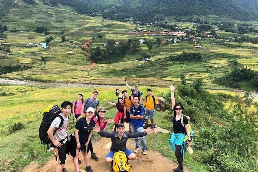 Een groep mensen wandelt over een onverhard pad, met een bergachtig landschap op de achtergrond. 3