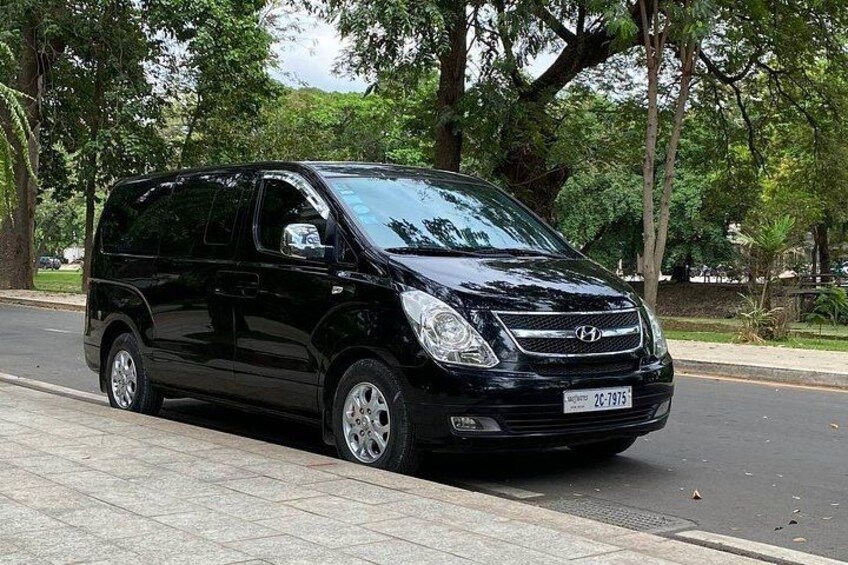 A black van parked on a paved road with trees in the background. 3