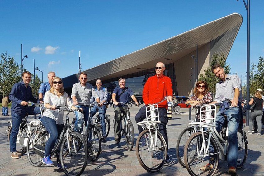 A group of people on bicycles in an urban setting with modern architecture. 1