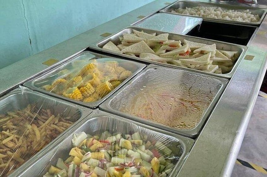 Un bufé con diferentes opciones de comida, como maíz, arroz, sándwiches y verduras. 5