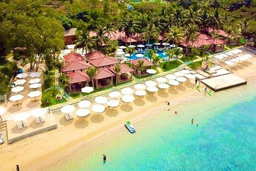 Un complexe hôtelier de bord de mer avec des parasols, une piscine et des palmiers. 3