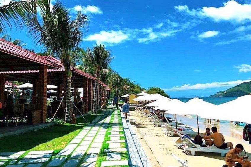 Un complexe hôtelier situé en bord de mer, agrémenté de palmiers, de parasols et de chaises longues. 4
