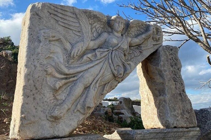 A large stone sculpture of an angel with wings, set against a clear sky. 5