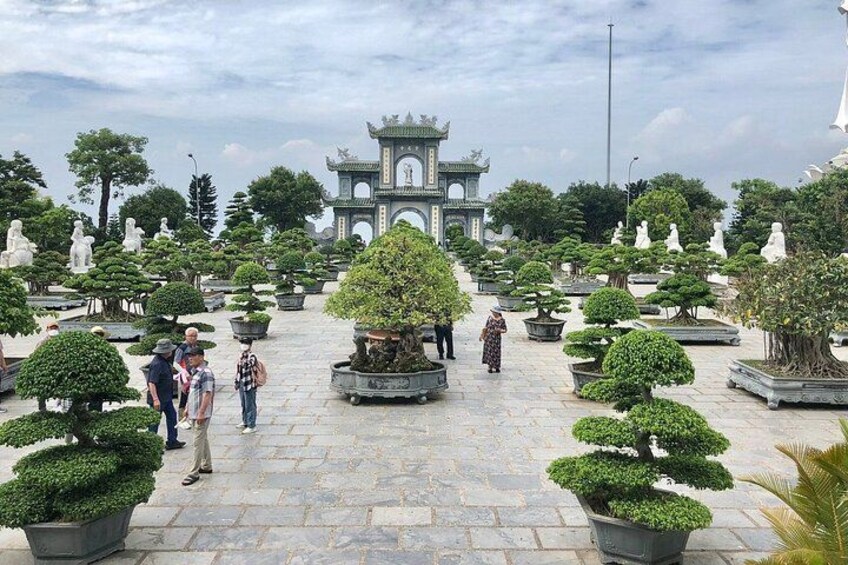 A traditional Chinese garden with stone pathways, neatly trimmed trees, and a pagoda in the background. 5