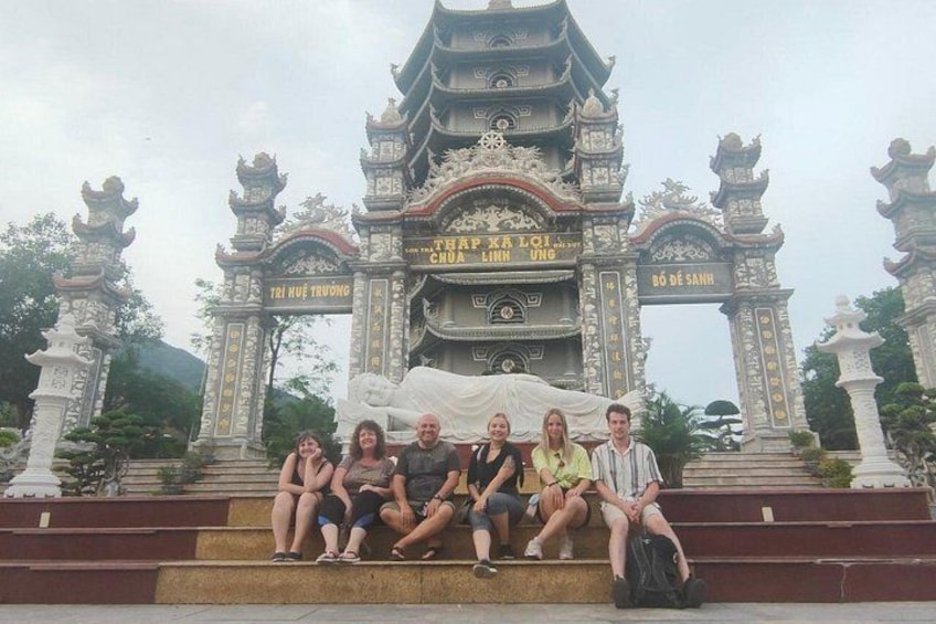 A group of people sitting on steps in front of a traditional gate with inscriptions. 3