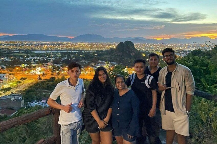 A group of people standing on a hill overlooking a cityscape at dusk. 4