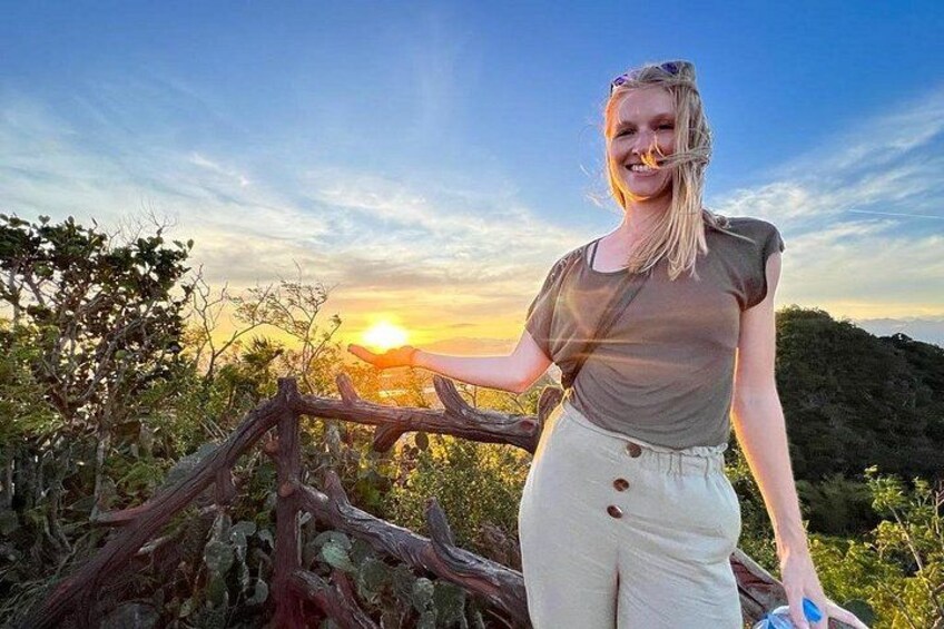 A person standing by a wooden fence with a sunset in the background. 1