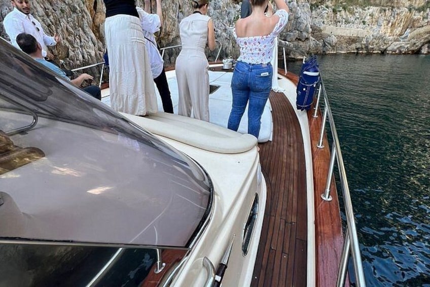 Een boot met mensen op het dek, rotsachtige kliffen op de achtergrond en rustig water. 3