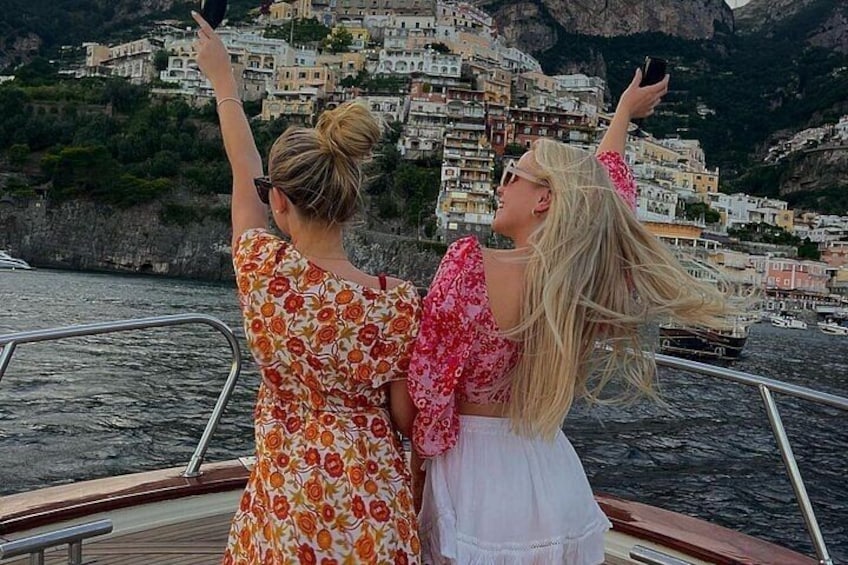 Twee personen op een boot, met een kustdorpje op de achtergrond. 4