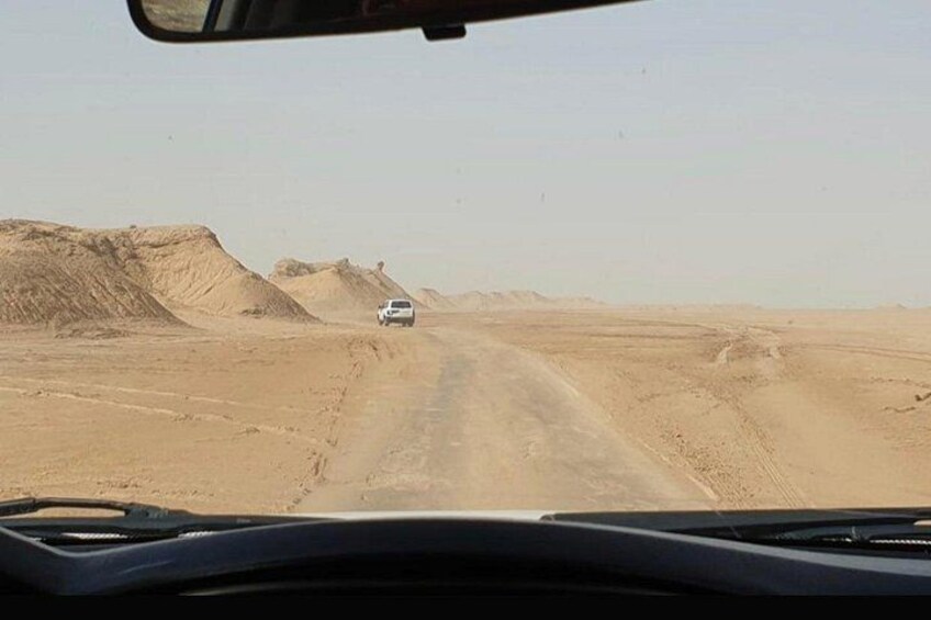 Ein Fahrzeug fährt auf einer unbefestigten Straße durch eine Wüstenlandschaft mit Sanddünen. 5