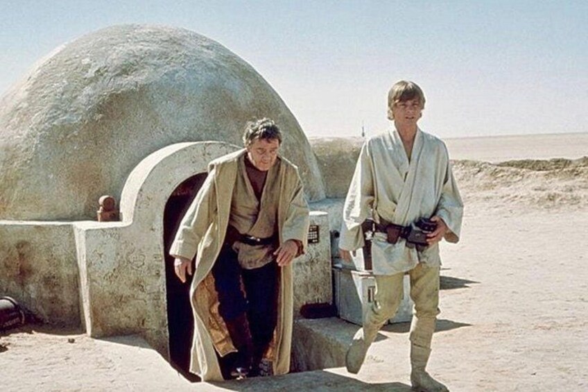 Zwei Personen in Jedi-Gewändern vor einer großen, kugelförmigen Struktur, möglicherweise ein Droide oder ein Gebäude. 4