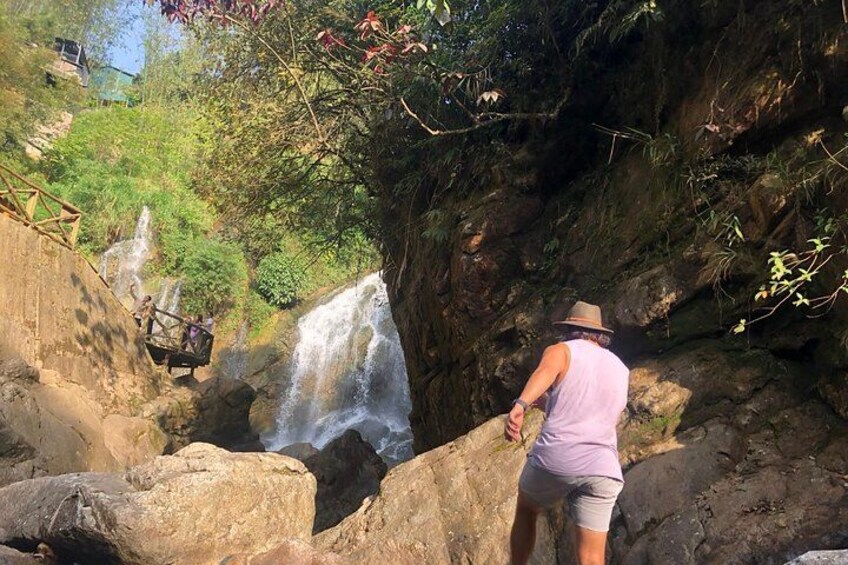 Ein Wasserfall, felsiges Gelände und eine Person in der Nähe des Wassers. 4