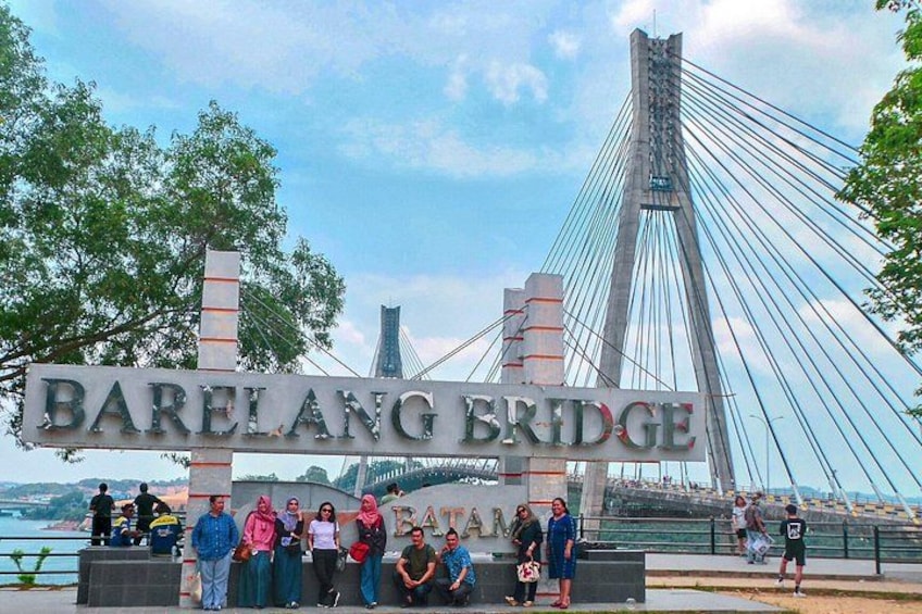 A sign for Barelang Bridge with a cable-stayed bridge in the background. 2
