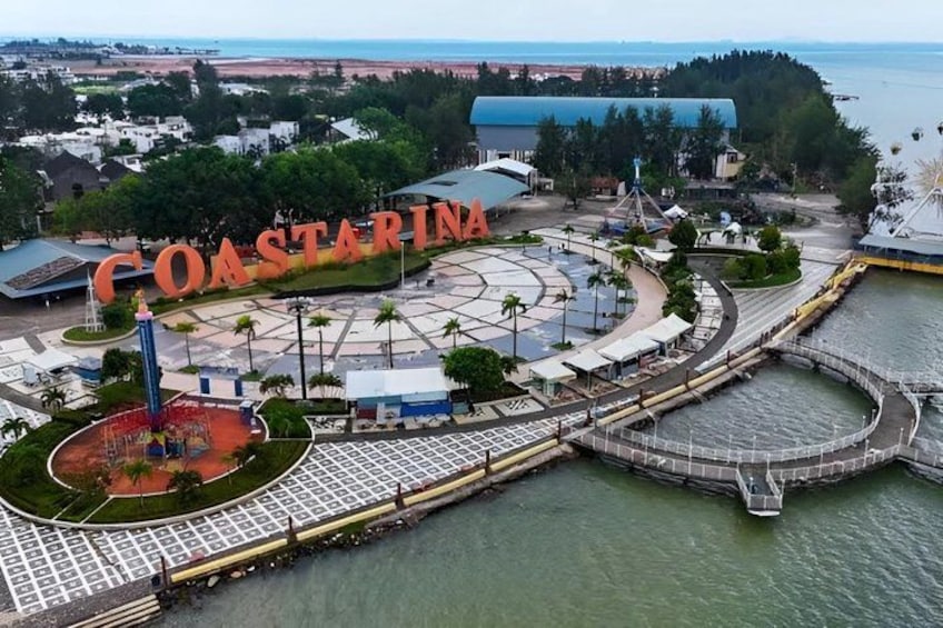 A coastal marina with a large sign reading 'COASTARINA,' a circular water feature, and a viewing platform. 1