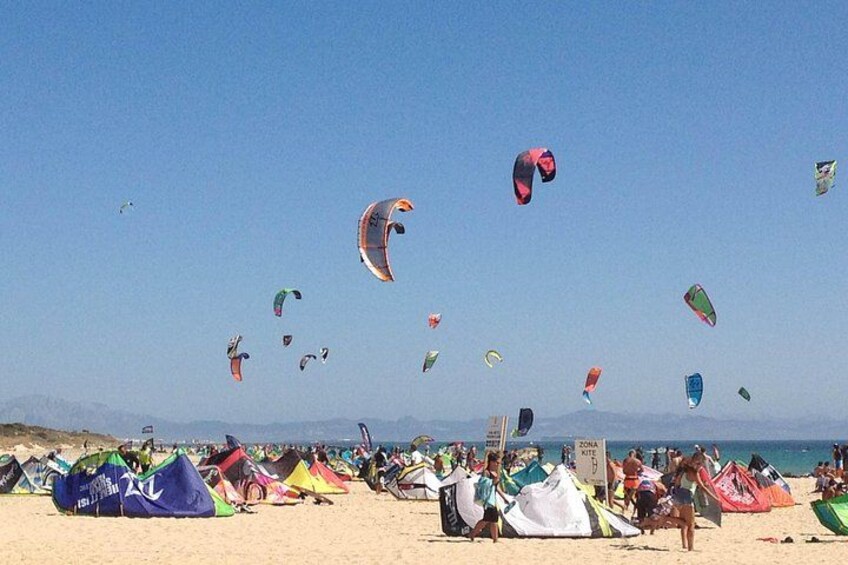 A beach with multiple colorful kites and tents. 4