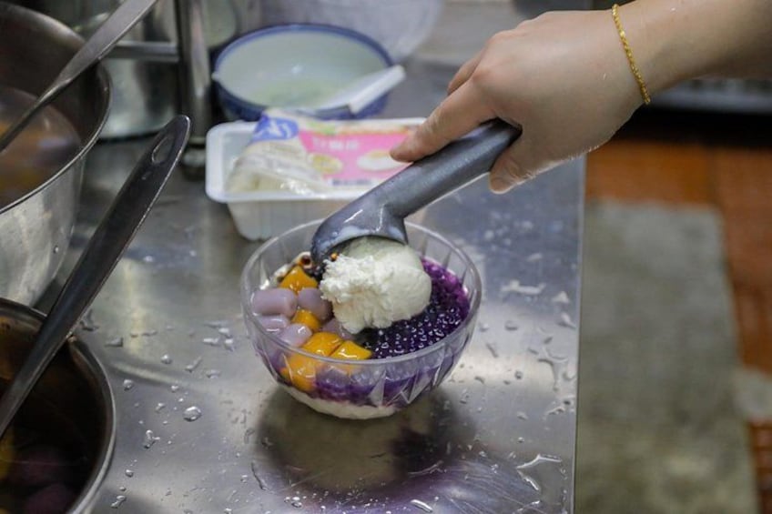 Une personne qui puise de la crème glacée dans un bol contenant des perles de tapioca violettes et jaunes. 3