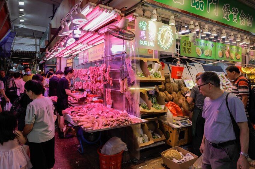 Een levendige markt met verschillende kraampjes voor eten, waaronder een met durian en een andere met diverse soorten fruit en groenten. 3