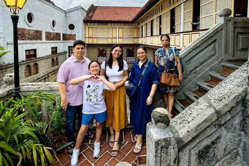 A group of people posing in front of a traditional building with a staircase. 4