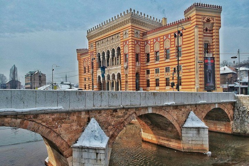 A historic building with ornate architecture, a stone bridge with arches, and a river in the foreground. 5