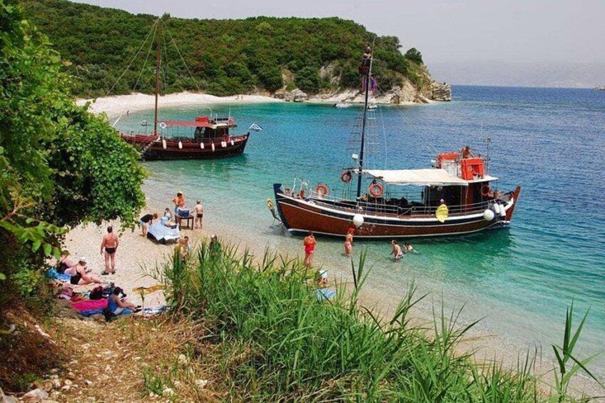 A beach with boats, people, and greenery. 1