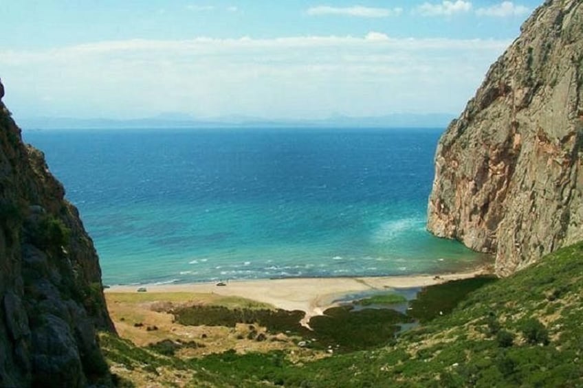 A coastal landscape with cliffs, a beach, and a clear blue sea. 5