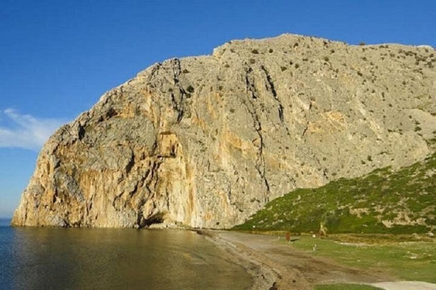 A rocky cliff by a beach with a clear sky. 3