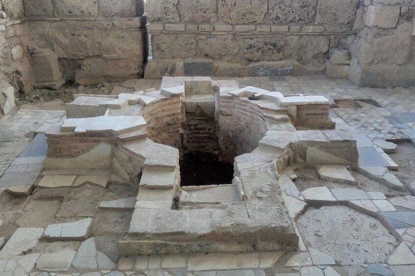 An ancient stone structure with a central circular opening surrounded by stepped platforms. 3
