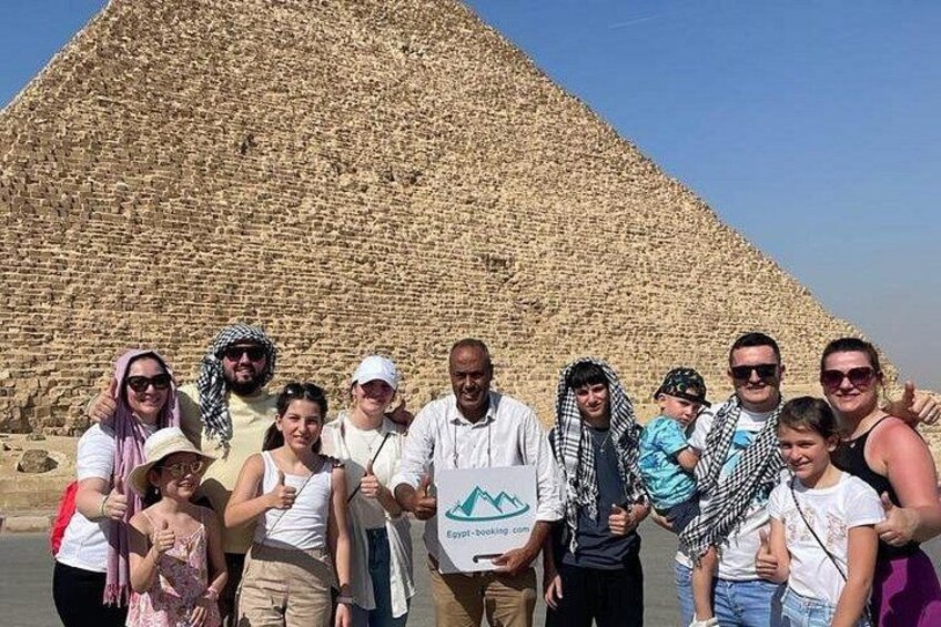 A group of people standing in front of a large pyramid. 4