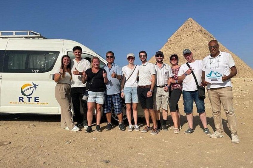 A group of people standing in front of a pyramid with a tour bus labeled 'RTE' in the background. 2