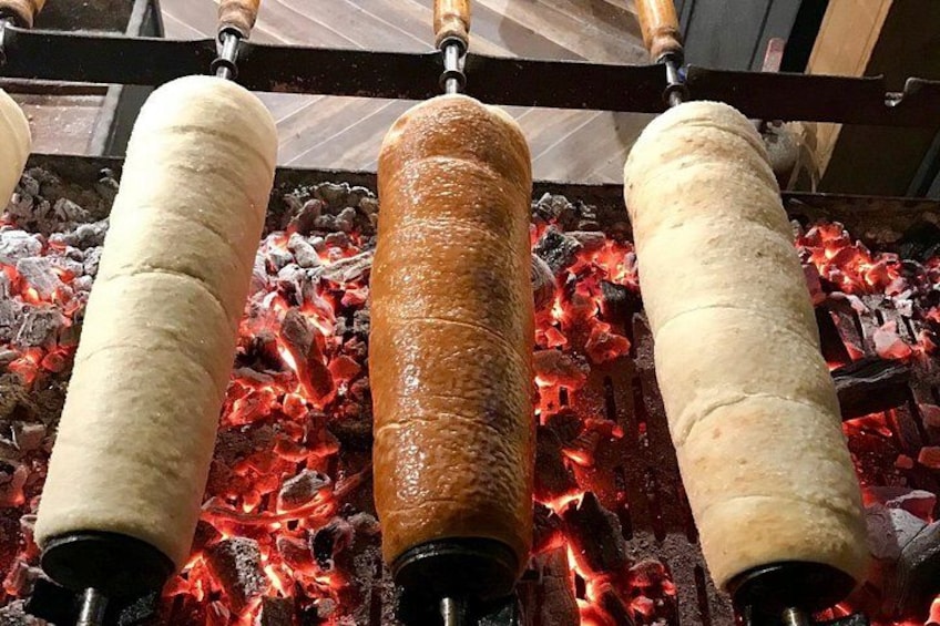 Un asador vertical con tres brochetas de carne asándose sobre fuego abierto. 2
