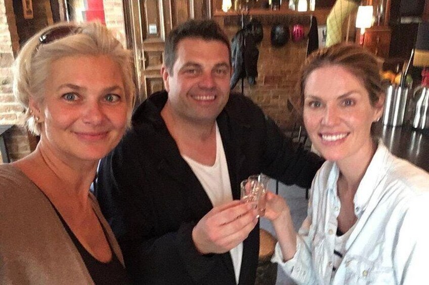 Tre personer skålar med drinkar i en bar med tegelväggar och olika flaskor i bakgrunden. 5