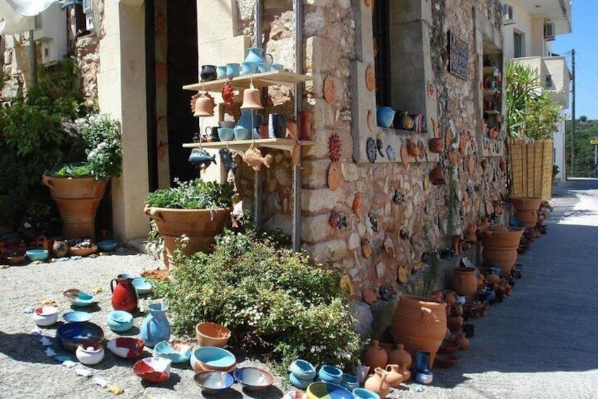 Un edificio de piedra con cerámica exhibida en estantes y macetas en el suelo. 1