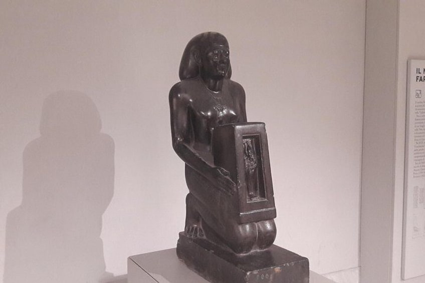 A sculpture of a seated figure with a rectangular object in front of it. 4