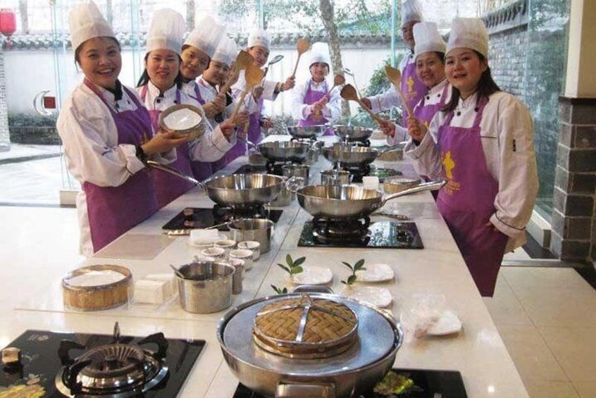 A group of chefs in white hats and purple aprons preparing food in a kitchen. 1