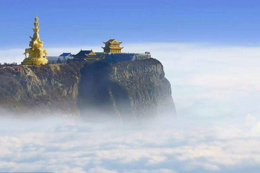 A cliffside with traditional architecture and a golden statue. 1