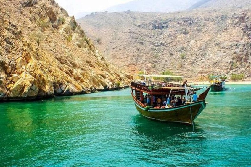 A boat on turquoise water surrounded by rocky cliffs. 1