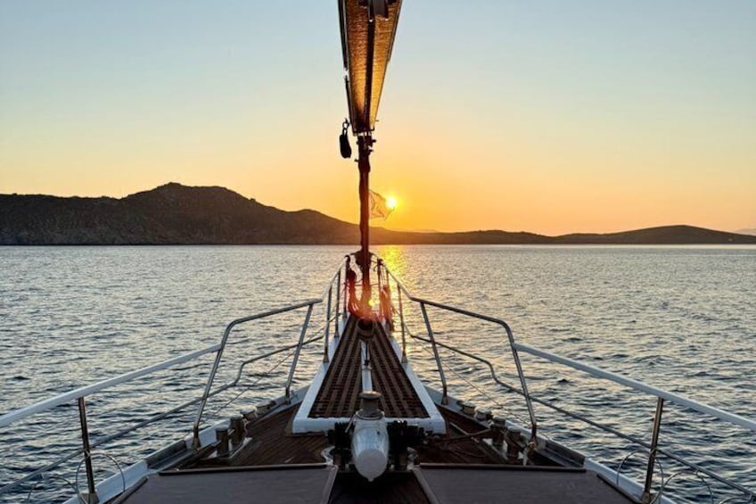 A boat deck with a view of the sunset over water and distant hills. 3
