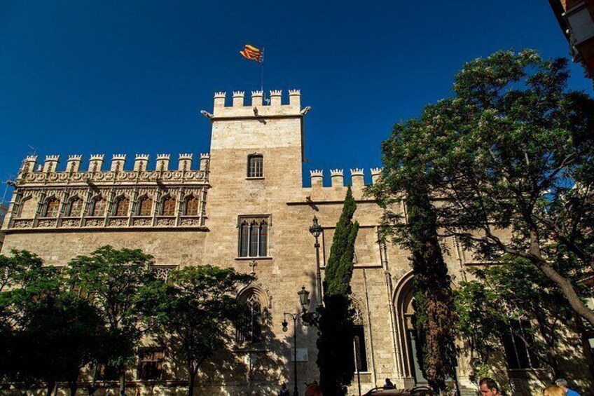 A historic building with a prominent tower, arched windows, and a flag. 3