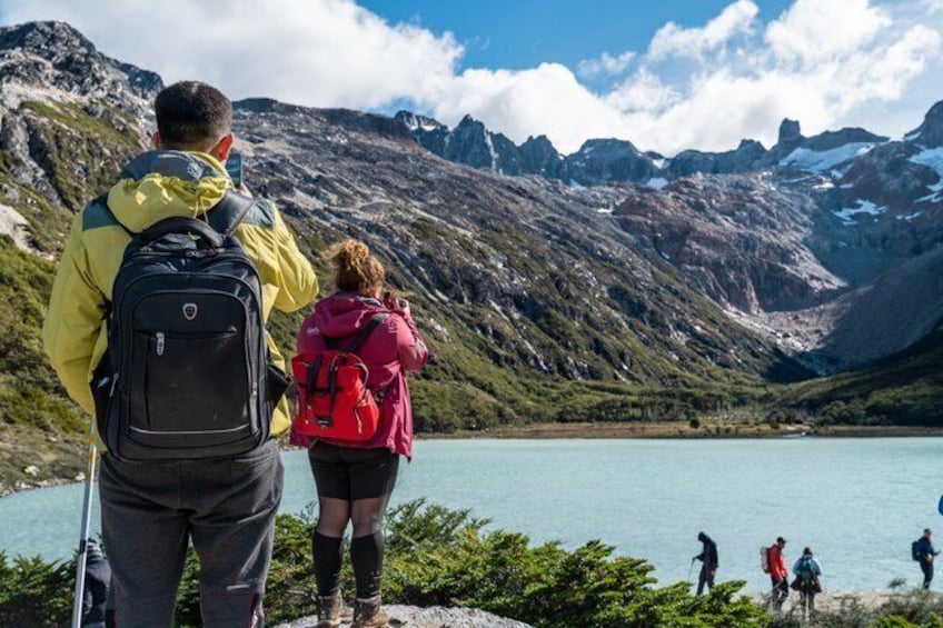 Hikers on a mountain trail with a lake and mountains in the background. 3