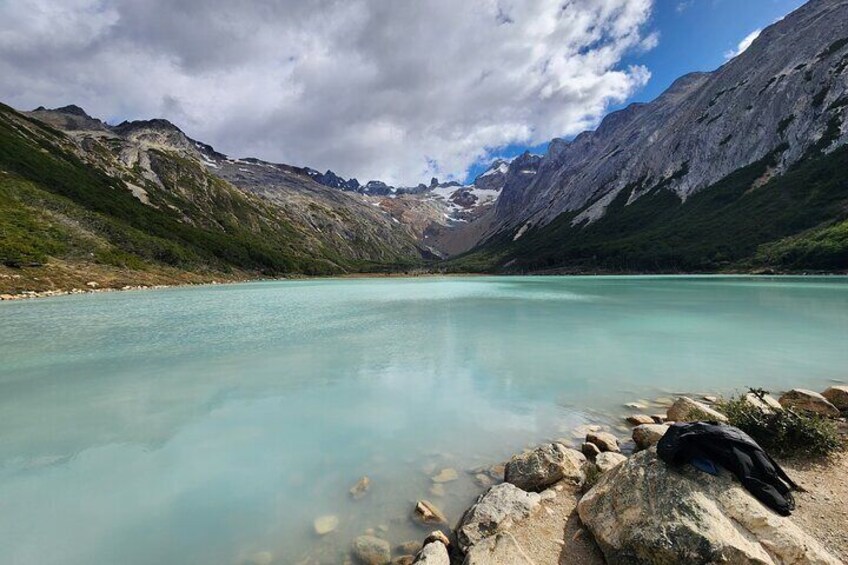 A mountain lake with clear turquoise water, surrounded by rocky shores and snow-capped mountains. 1